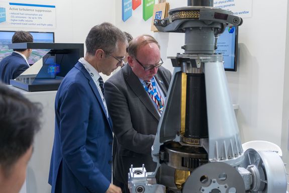 visitor and ehibitor talking infornt of the helicopter gearbox at the TU Wien stand