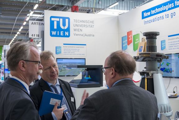 three man talking at the TU Wien Stand