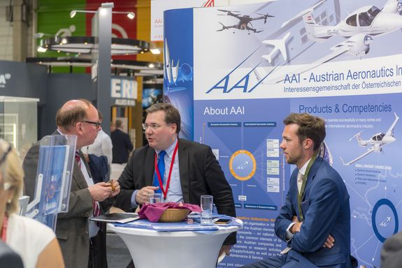 three men talking at the AAI stand