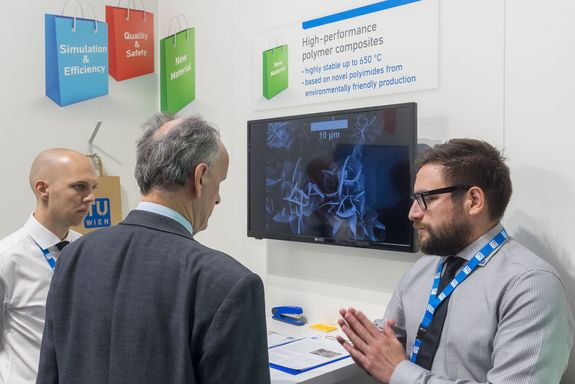 three men infront of a monitor at the TU Wien stand