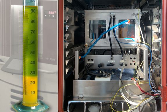 Links eine Flüssigkeit, die unten feste Ausflockung zeigt, rechts der Prüfstand mit zahlreichen Kabeln
