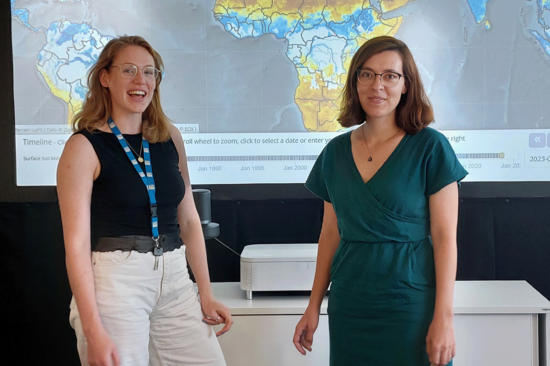 Johanna Lems and Ruxandra-Maria Zotta from the CLIMERS group in front of a screen displaying a climate image they created. Both are smiling.
