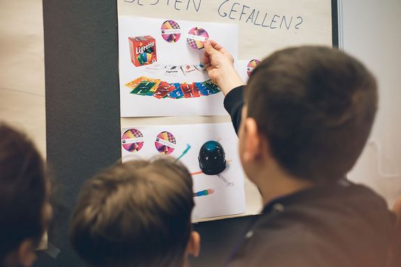 Children stick stickers on a paper on the wall