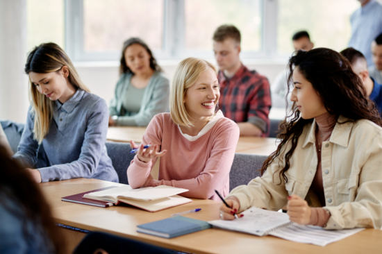 Blick in einen Vorlesungsraum. Zwei junge Studierende sind im Gespräch vertieft