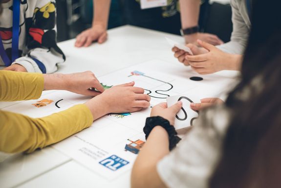 hands of children while working on a poster together