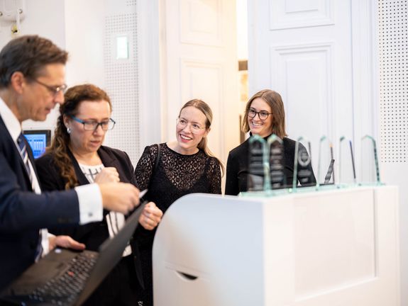 immQu Awards are ready, four participants are standing in front of them.