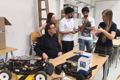 Professor and students discussing. Model racing car in the front.