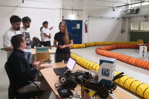 Professor and students discussing. Model racing car in the front.