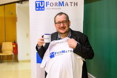 Portrait des Vortragenden, wie er TUForMath Tshirt und Tasse hochhält